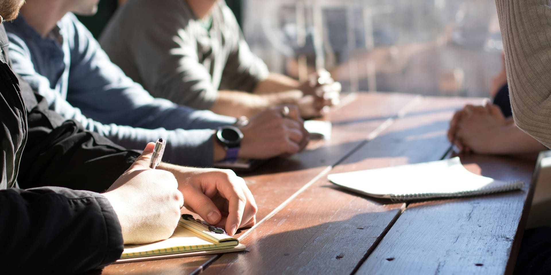 Equipo de trabajo tomando notas alrededor de una mesa de reunión